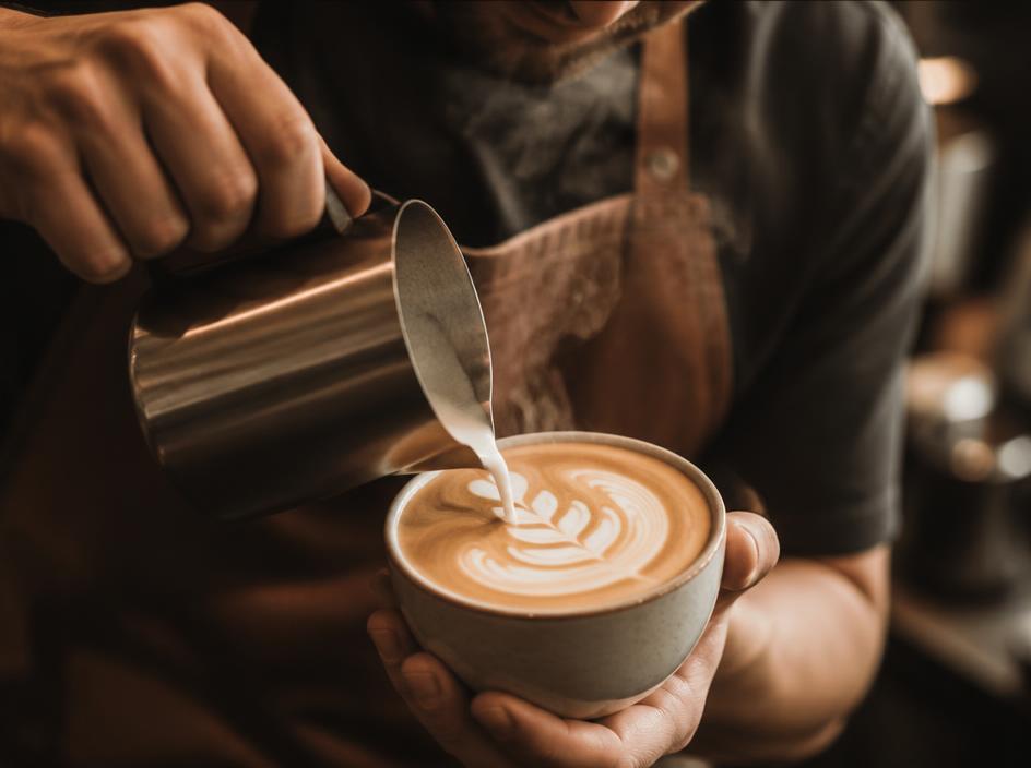 Barista pouring latte art into a ceramic cup